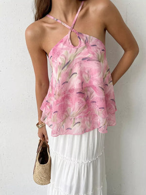 Vibrant floral halter cami with keyhole cutout and ruffle hem, styled with a white tiered skirt.