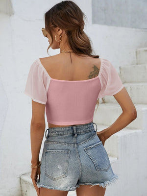 Pink ribbed crop top with sheer puff sleeves and square neckline.
