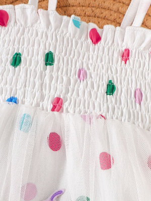 White smocked bodysuit dress with colorful polka dot ribbon details and tulle skirt.