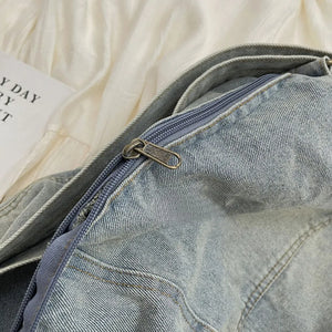 Light washed denim hobo bag with a zippered closure and antique brass hardware.