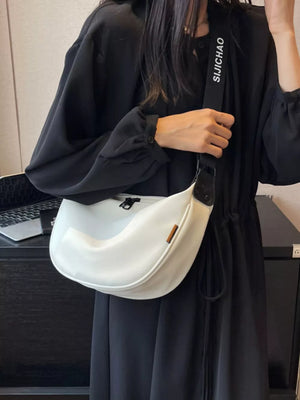 White crescent crossbody bag with adjustable strap and zip closure.
