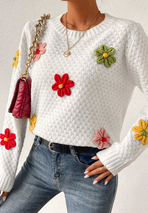 White crochet knit sweater with colorful floral embellishments and a textured pattern.