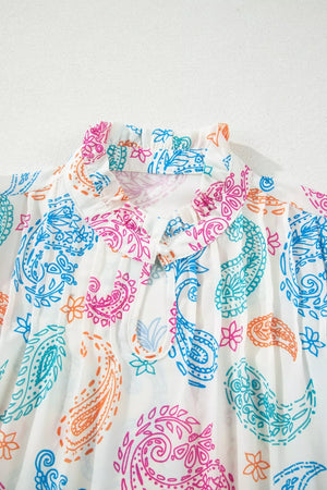 Maternity blouse with vibrant paisley print, ruffled neckline, and tie cutout.