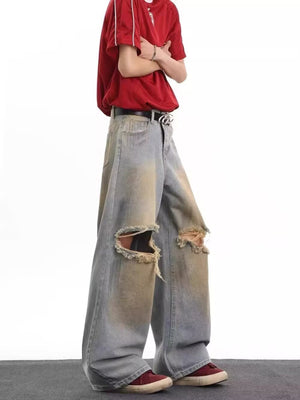 Men's distressed wide leg jeans in blue denim with large ripped knees and faded details.