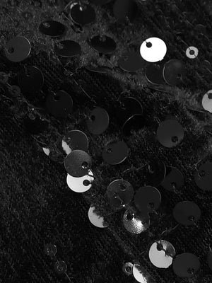 Black sequin maxi gown detail with scattered round sequins on textured fabric.