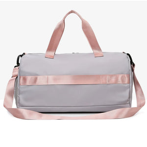 Gray duffel bag with pink straps and buckle detail, perfect for gym or travel.