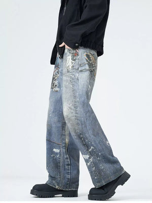 Men's wide-leg jeans in dusty blue denim with paint splatters and graphic pocket details.