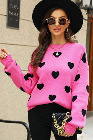 Pink knit sweater with black hearts, crew neck, and balloon sleeves.