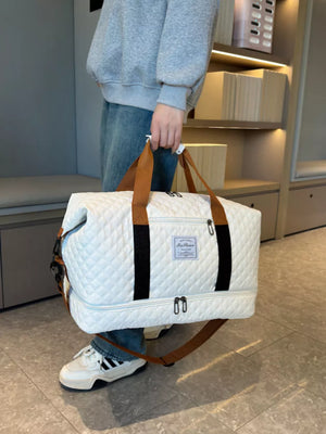 Creamy-white quilted duffel bag with brown straps and black accents.