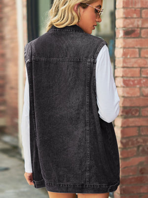 Black longline denim vest with utility pockets and collared neckline, worn over a white long-sleeve shirt.