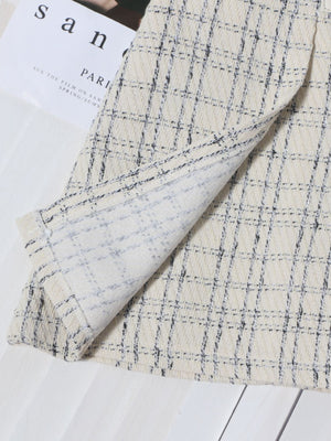 Beige plaid mini skirt with ruched detail and belt, showing fabric texture.