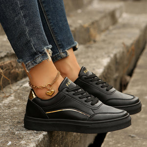 Black lace-up casual sneakers with gold accents and a heart charm anklet.