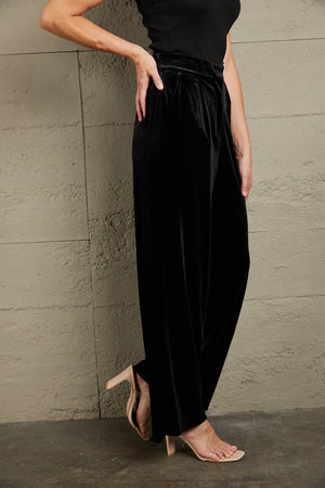 Black velvet palazzo trousers with high waist and wide leg, shown on a model.