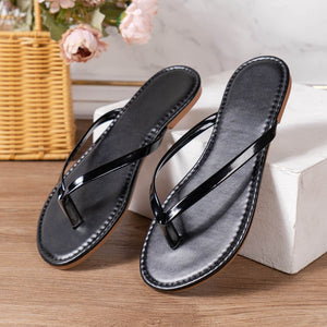 Black patent leather toe-post sandals with thin straps and a minimalist design.