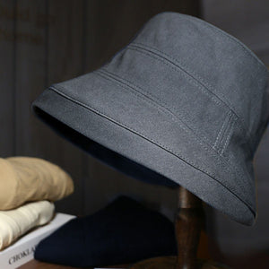 Dark gray cotton bucket hat with stitched details and a wide brim.