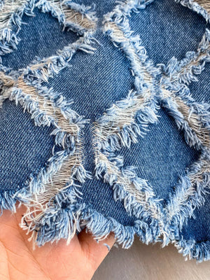 Distressed denim shorts with frayed diamond cutouts and raw hem detail.