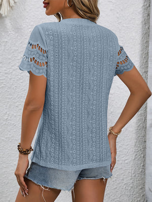 Light blue eyelet blouse with scalloped short sleeves and geometric pattern.