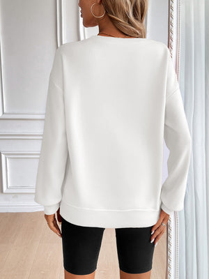 White relaxed fit sweatshirt with crewneck and long sleeves, styled with black biker shorts.