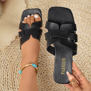 Black woven strap slide sandals with square toe and "Fashion" detail on sole.