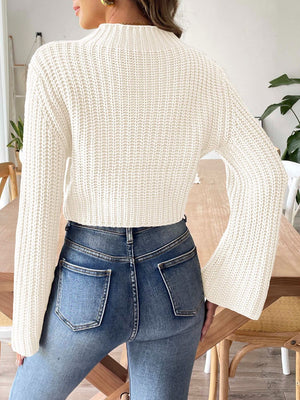 White ribbed crop sweater with bell sleeves and mock neck, styled with jeans.