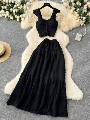 Black textured two-piece set with ruffled crop top and tiered maxi skirt.