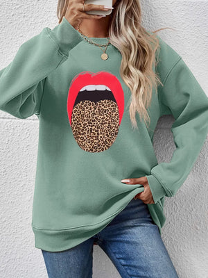 Sage green sweatshirt with a bold red lips and leopard tongue graphic.