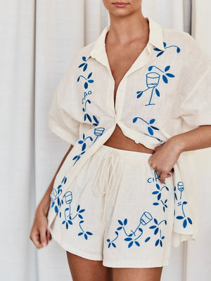 Embroidered linen co-ord set in cream with blue floral and wine glass embroidery, featuring a button-up shirt and drawstring