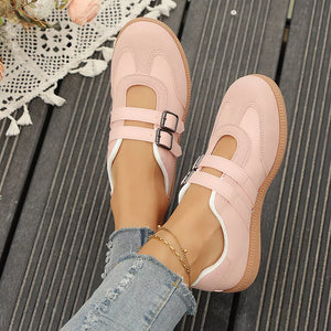 Pink buckle strap Mary Jane inspired sneakers with double buckle detail and white trim.