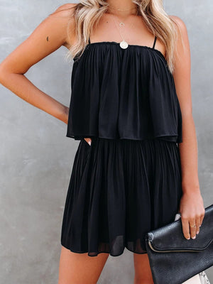 Black tiered cami romper with delicate straps and pleated skirt detail.