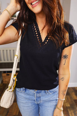 Black polyester tee with embroidered cutout V-neck and short sleeves.