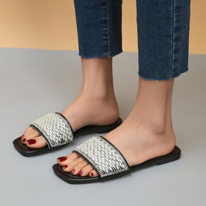 Black slide sandals with pearl and rhinestone embellished straps.