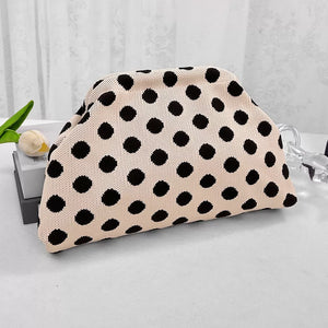 Knit clutch bag with black polka dots on a light pink background.