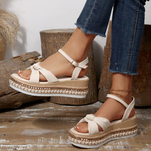 Beige bow knot wedge sandals with braided trim and ankle buckle.