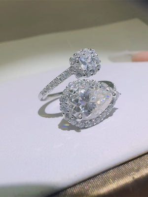 Silver bypass ring with pear and princess cut diamond halo details.