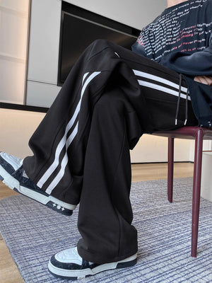 Men's black wide-leg sweatpants with white side stripes and drawstring waist.