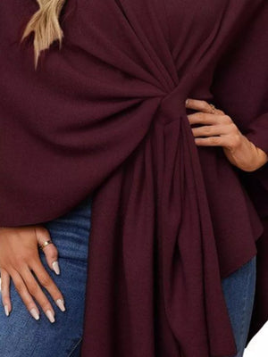 Burgundy knit cape top with draped front tie detail and wide sleeves.