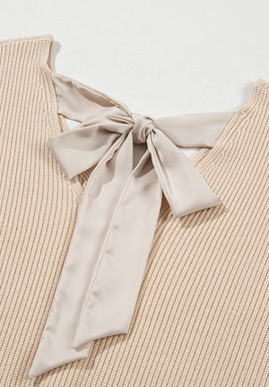 Beige ribbed knit sweater with a satin bow detail at the back neckline.