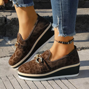 Brown leopard print wedge loafers with buckle detail and platform sole.