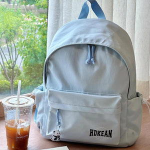 Blue nylon backpack with front pocket, drawstring closure, and panda charm.