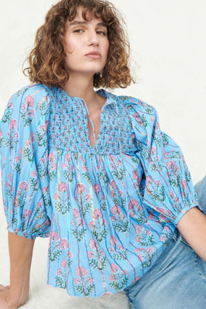 Sky blue floral print smocked yoke blouse with puff sleeves and tie neck.