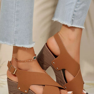 Brown crisscross high heel sandals with studs and adjustable strap, featuring a block heel.