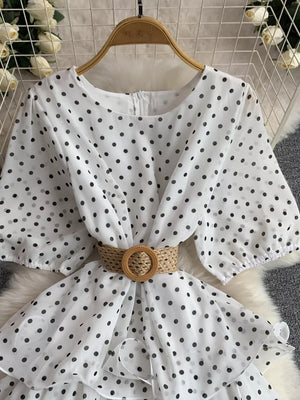 White polka dot tiered dress with puff sleeves and a woven belt.