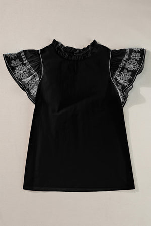 Black blouse with ruffled neckline and embroidered flutter sleeves.
