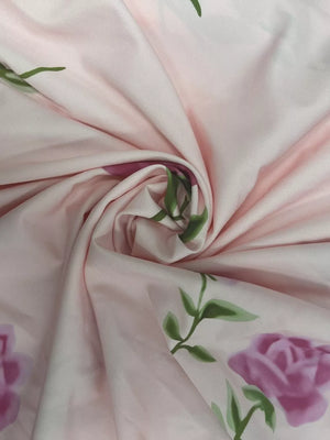 Blush pink floral print maxi dress fabric detail with purple roses and green leaves.