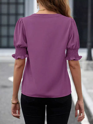 Purple blouse with puffed sleeves and smocked cuffs, V-neck detail.