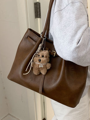 Brown leather shoulder bag with buckle detail and teddy bear charm