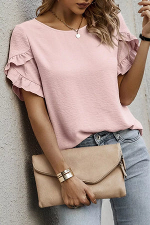 Blush pink polyester blouse with ruffle trim short sleeves and a textured finish.