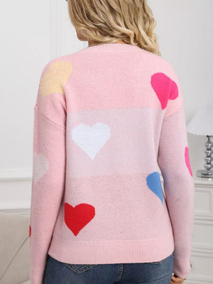 Pink acrylic sweater with a colorful heart pattern and round neck.