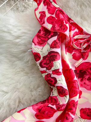 Charming floral ruffle trim mini dress with pink and red roses, featuring a bow detail.