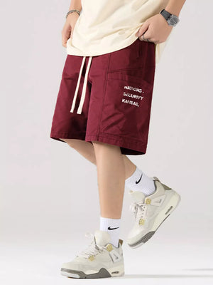 Maroon red cotton cargo shorts with adjustable drawstring and white text detail.